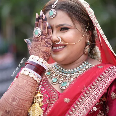 A happy bride showing off her beautiful mehndi stain. The deep reddish brown color of the henna looks stunning against her bridal attire and jewelry. This is the result of good henna and proper aftercare.