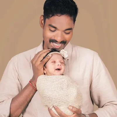 A father's gentle hold and a baby's happy smile. This candid moment between a dad and his daughter is what family portraits are all about.