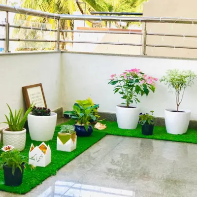 A full view of the balcony makeover for my client Spoorti. I combined a variety of plants in different white and decorative pots, arranged on artificial grass mats, to create a complete and cohesive garden space that feels both clean and vibrant.