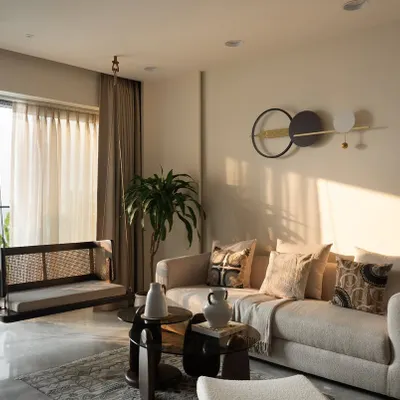 Golden hour in Project 'Sukoon'. This living room is a perfect example of warm minimalism, where soft neutrals, a comfortable boucle sofa, and a handcrafted cane swing come together to create a space of pure tranquility.