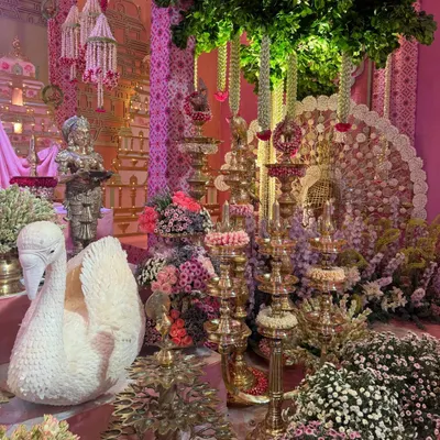 An opulent display for Anant and Radhika’s Raas Garba, where a magnificent swan crafted from flowers sits amongst tiered brass lamps and lush floral arrangements. This setting was part of a larger design celebrating divine love with traditional Indian decor elements.