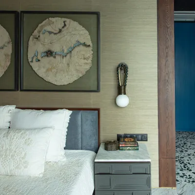 The younger daughter's bedroom features custom wall art made from straw pulp, thread, and jute. The bedside table and light are custom-designed by our furniture studio, Furgonomics, creating a unique and personal space.