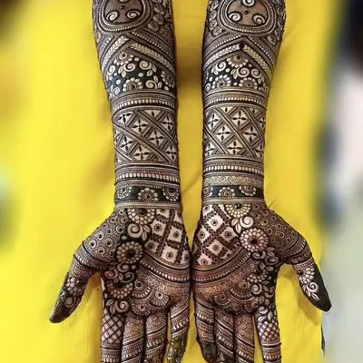 A stunning example of symmetrical, full-coverage mehandi featuring geometric checks, floral bands, and paisleys for a timeless bridal look.