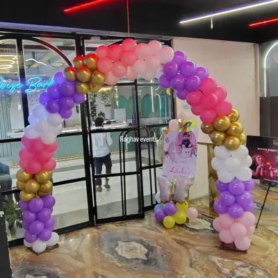 A beautiful balloon arch designed for a birthday party entrance. This one uses a theme of pink, purple, white, and gold balloons to create an inviting and celebratory entryway for guests.