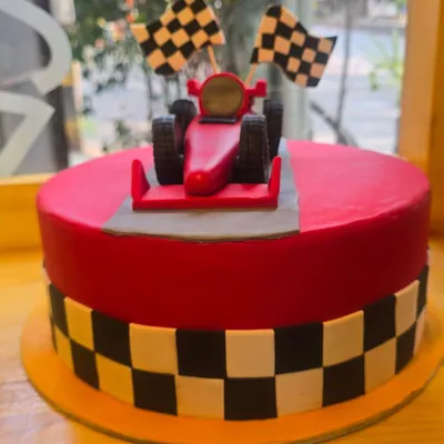 A red racing car and chequered details top our birthday cake, with black-and-yellow blocks around the side.