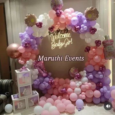 A beautiful "Welcome Baby Girl" shower. This circular balloon arch in pastel pink, purple, and white includes a neon sign and clear "BABY" blocks for a modern and sweet look.