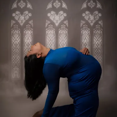 This is a powerful camel pose from a prenatal yoga session. It beautifully showcases the mother's flexibility and strength, with the artistic window-like lighting adding a spiritual feel.