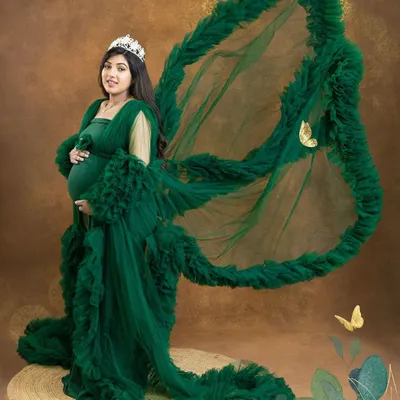 Feel like a queen in this dramatic portrait. The emerald green ruffled gown with its wing-like fabric toss and a delicate tiara creates a truly majestic and unforgettable look.