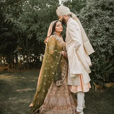 A beautiful, serene portrait of a couple on their wedding day. The groom's gentle kiss on the bride's forehead captures a moment of quiet love and affection amidst the celebration.