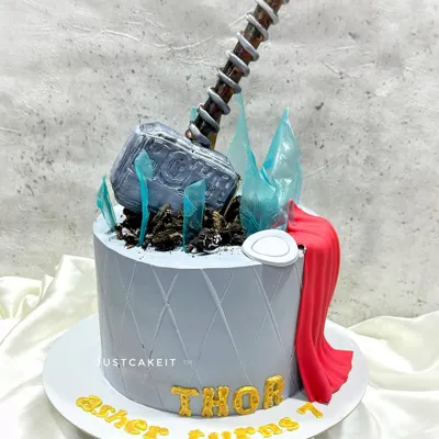 This Thor-themed cake is worthy of an Avenger, with an entirely edible Mjolnir hammer, sugar glass shards, and a flowing red cape. The details are crafted to look realistic and powerful.
