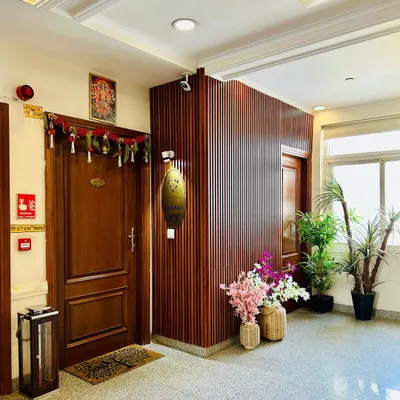 I designed this entryway to be warm and welcoming, using vertical wood fluting to add texture and warmth. The space is personalized with a custom nameplate and softened with potted plants and decorative flowers, creating an inviting first impression.