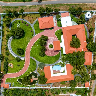 An aerial masterplan view of our Greenfield farmhouse project. The layout was meticulously planned to include a winding driveway, distinct zones for living and leisure, and lush landscaping that envelops the entire property.