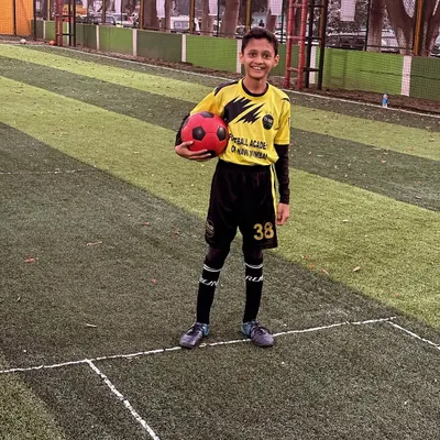 A young player poses with a ball, full of confidence after a great training session.