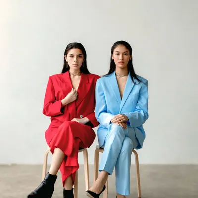 Two models, one in a red suit and one in blue, sit side-by-side, creating a powerful image of contrast and symmetry. This is a perfect example of a conceptual brand shoot.