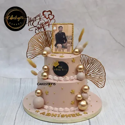 A personalized two-tier butterscotch cake for a special birthday. This elegant design features an edible photo frame, golden decorative balls, and delicate dried fern accents.