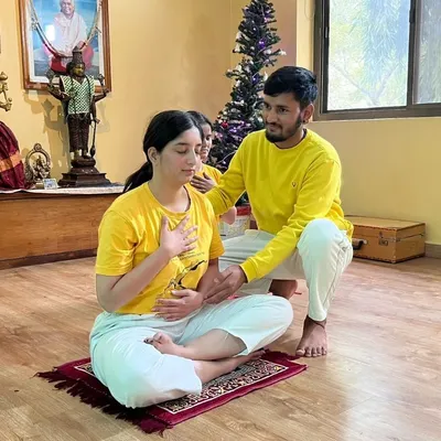Guiding a student in a pranayama class to ensure correct hand placement and breathing technique. Proper form is essential to experience the full benefits of controlling the prana, or life force.