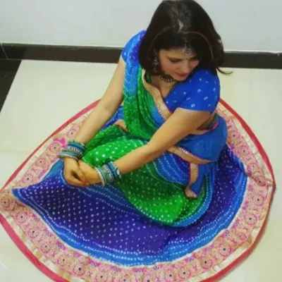 A top-down view of a custom dandiya lehenga, showcasing the full circle of the skirt in a traditional blue and green bandhani print.