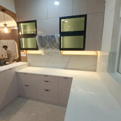 A look at a modular kitchen in progress at our ATS Rhapsody site. This U-shaped kitchen features a quartz countertop and backsplash, with under-cabinet lighting to illuminate the workspace.