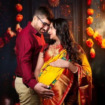 A beautiful moment between a couple during their traditional maternity shoot. The warm glow from the diyas and marigold decor perfectly complements the rich colors of their ethnic attire.