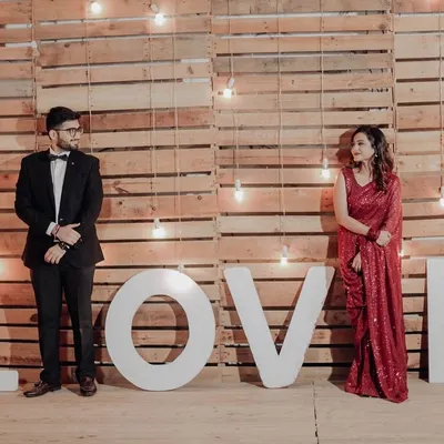 Our 'LOVE' marquee letters set against a rustic wooden wall with hanging bulbs. This is one of our most popular setups for romantic evening shoots.