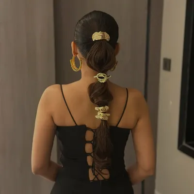 A full view of the bubble ponytail with gold accessories. This modern hairstyle is perfect for making a fashion-forward statement at parties or events.