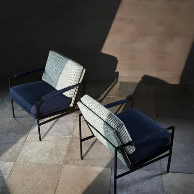 Two modern armchairs captured from above, with dramatic lighting highlighting their form and texture. This artistic shot focuses on the interplay between light, shadow, and upholstery.