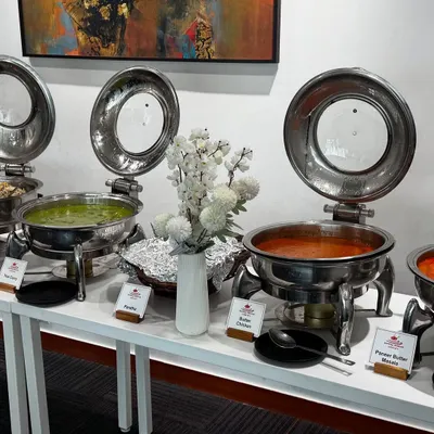 A professional buffet line we organized for a corporate lunch. The setup features a variety of main courses in stainless steel chafing dishes, clearly labeled for guests, ensuring an organized and high-quality dining experience.