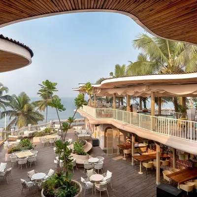An elevated view of Dubki, showing how the organic, wave-like roof structure frames the stunning ocean view. The multi-level design provides various seating areas, all oriented towards the sea.