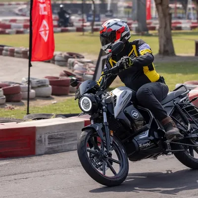 An action shot of the Revolt electric motorcycle cornering on a racetrack. Capturing the bike in motion with a rider in full gear adds a sense of speed and performance.