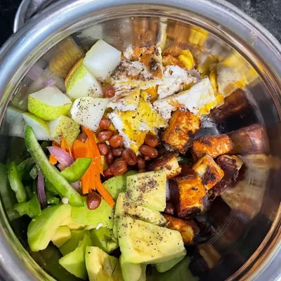 A client's vibrant and protein-packed salad bowl with paneer, avocado, peanuts, and fresh vegetables, tailored for their specific nutritional needs.