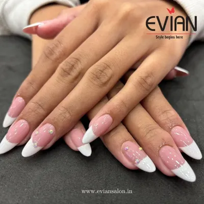 A perfect example of a classic French manicure on elegant, oval-shaped nails. The clean lines and subtle rhinestone accents make this a timeless choice for any event.