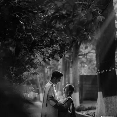A classic black and white shot, beautifully lit by a ray of sun. This image has a timeless, cinematic quality, focusing entirely on the couple's romantic interaction.
