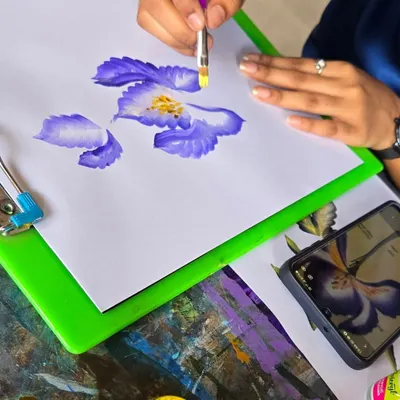 A student practices the one-stroke painting technique to create delicate flower petals. This method is fantastic for learning brush control and is used in everything from canvas art to nail art.