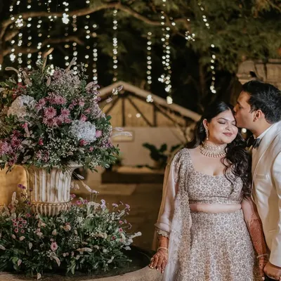 A kiss of love and appreciation. This tender moment between the couple, captured by the flower-adorned fountain, is a beautiful testament to their connection and the romantic atmosphere of their cocktail party.