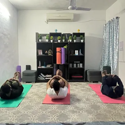 Students in my group class practicing a variation of Pavanmuktasana, the Wind Relieving Pose, to aid digestion and release tension in the lower back. The screen in the background often guides our meditation visuals.