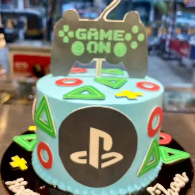 Game on! This PlayStation-themed cake is the perfect level-up for any gamer's birthday. It features the iconic controller symbols, the PS logo, and a "Game On" topper.
