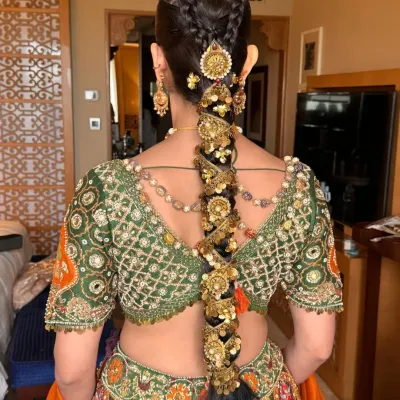 A close-up of a traditional jeweled braid, showing the detailed placement of each gold accessory. This style is built to last through long ceremonies while supporting the weight of other hair ornaments.