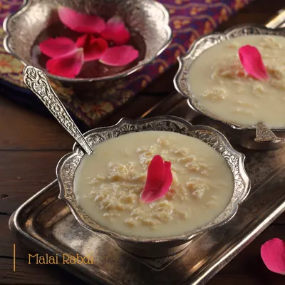 Our homemade Malai Rabdi, served in traditional silver bowls. This dessert is made by simmering milk for hours until it thickens, sweetened just right, and garnished with rose petals.