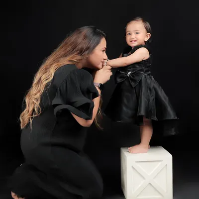 A simple yet profound gesture of a mother kissing her daughter's hand. Set against a dramatic black background, this image isolates the moment, emphasizing the tenderness and love in their relationship.