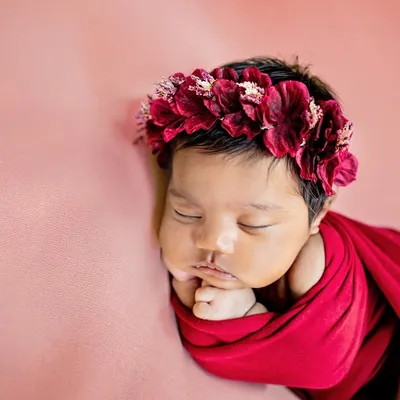 This little one looks like a beautiful rose, wrapped in red with a delicate floral crown. I use a variety of colorful wraps and props to style your newborn session.