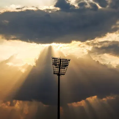 The calm before the storm. A dramatic shot of the stadium floodlights as the sun sets, building anticipation for the night's game.