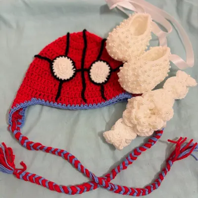Assemble the cutest hero with this Spider-Man inspired set. It includes a character beanie, matching white pearl booties, and a white headband.