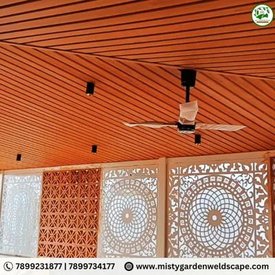 A stunning view of a completed terrace room featuring a combination of intricate white CNC panels and classic red jali bricks. The warm wood-finish PVC ceiling adds to the luxurious feel of this beautifully designed space.