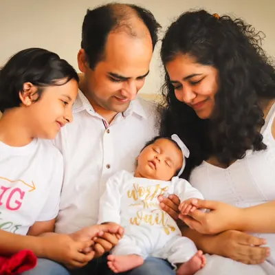 A perfect example of an at-home session. The whole family, dressed in white, admiring their new baby in the comfort of their own space.