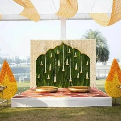 This stunning outdoor Haldi mandap is inspired by South Indian temple architecture, using a banana leaf wall and a floral arch to create a sacred and beautiful space.