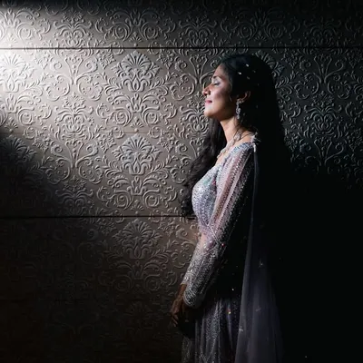 A moment of quiet reflection for the bride. We used a single sliver of light to create this dramatic, artistic portrait that highlights her serene profile and elegant gown.