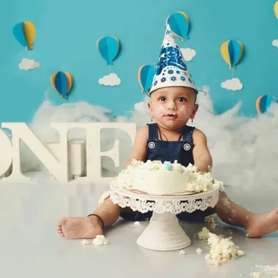 The aftermath of a successful cake smash. This little one is wearing a birthday hat and a face full of frosting, a perfect memory of his first birthday.
