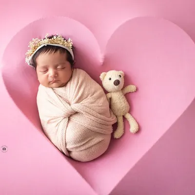 Your love, all wrapped up. A newborn sleeps peacefully inside a heart-shaped prop, a perfect symbol of a new love.