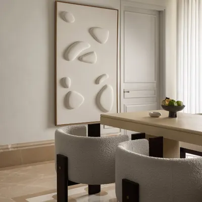 The dining room at Ecru Maison blends calm minimalism with sculptural elegance. We designed a soft-toned dining table and paired it with boucle chairs framed in dark wood for balance and comfort.