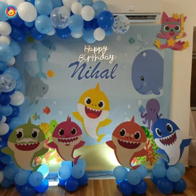 This Baby Shark party for Nihal's birthday was a dive into fun. The backdrop featured the whole shark family as cutouts against an ocean scene, framed by a blue and white balloon arch that mimics bubbles.